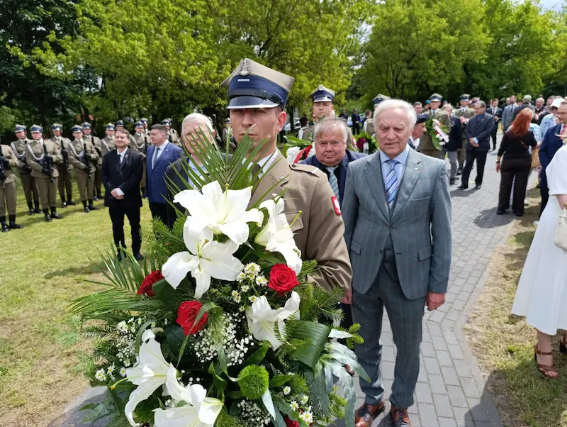 Delegacja podążająca za żołnierzem niosącym biało-czerwoną wiązankę